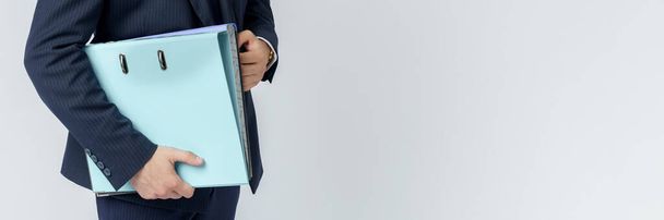 Businessman in a blue suit holds a folder in his hands on a white background. No face visible. - 写真・画像