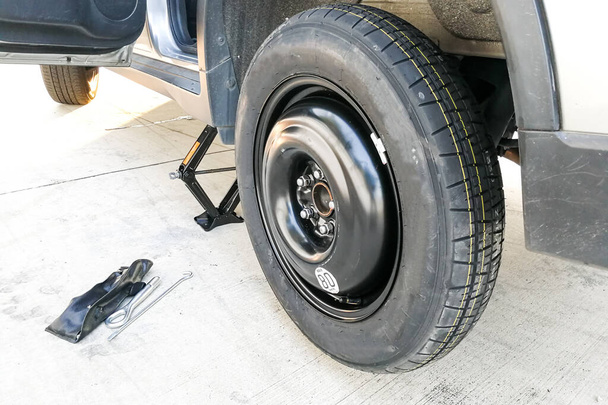 Pneu de emergência temporário substituído na roda do carro após pneu furado
. - Foto, Imagem