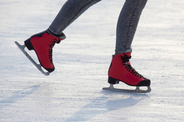 Füße in roten Schlittschuhen auf einer Eisbahn. Hobbys und Freizeit. Wintersport - Foto, Bild