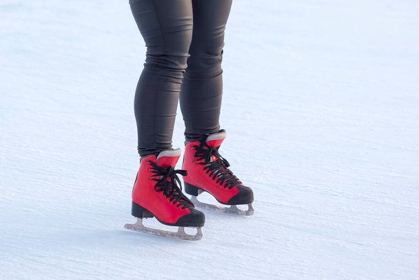 piernas de una chica patinando sobre hielo en una pista de hielo. pasatiempos y ocio. deportes de invierno - Foto, Imagen