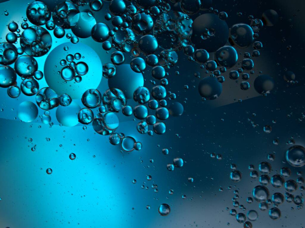 Hermoso aceite de burbujas abstractas en el agua con fondo negro azul oscuro, imagen macro, color dulce, gotas, borrosa, brillante - Foto, Imagen
