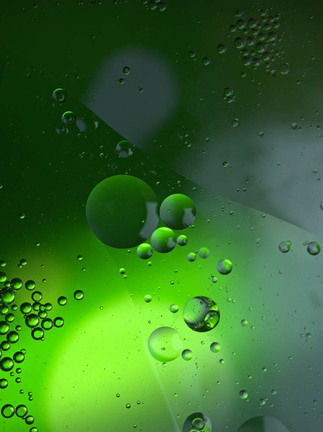 Hermoso aceite de burbujas abstractas en agua con fondo borroso brillante verde, imagen macro, color dulce, gotas - Foto, imagen