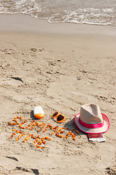 Inscription summer time made of amber stones, accessories for sunbathing and passport with currencies dollar on sand at beach. Sunbathing, travel and vacation time - Foto, Imagen