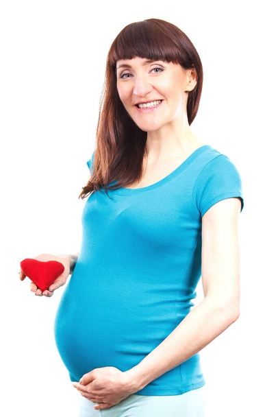 Happy smiling woman in pregnant holding heart and hand on her belly, symbol of new life, expecting for newborn and extending family - Fotografie, Obrázek