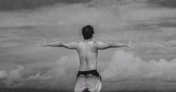 Zwart-wit animatie van een man met open armen in een regenachtige dag, zware wolken op de achtergrond. Concept van vrijheid gevoelens of religieuze aspecten zoals praten met God of de hemel. Animatie. - Video