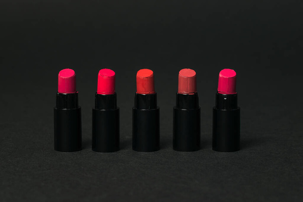 Five samples of red lipstick on a black background. - Photo, Image