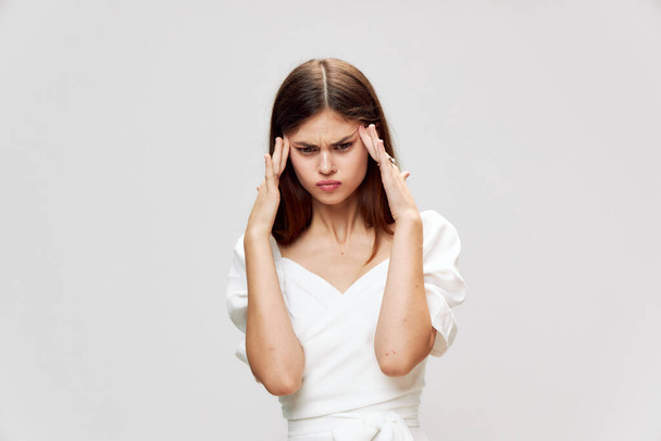 Nespokojená žena bolest hlavy ruce v blízkosti obličeje bílé šaty oříznuté pohled  - Fotografie, Obrázek