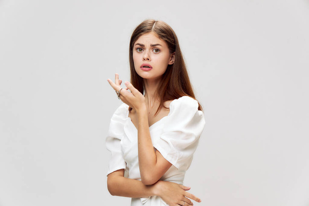 emotional woman looking straight white dress studio gray background  - Foto, Imagem
