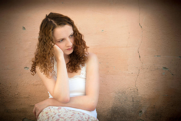 Ulkona muotokuva surullinen nuori nainen etsivät harkittuja ongelmia edessä likainen seinä - Valokuva, kuva