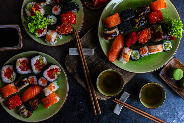 Conjunto de sushi com vários sashimi, rolos de sushi e chá servido em ardósia de pedra - Foto, Imagem