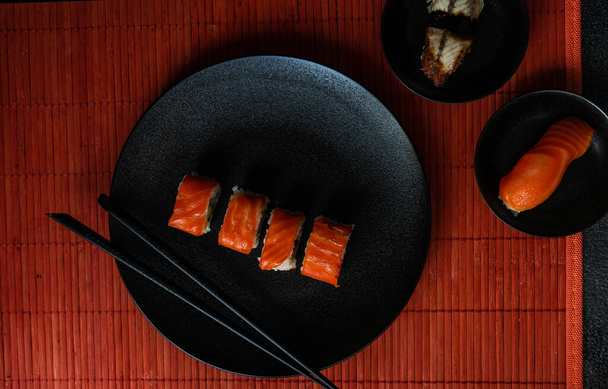 Sushi-Set mit Philadelhia-Rollen serviert auf Steintisch mit Essstäbchen - Foto, Bild