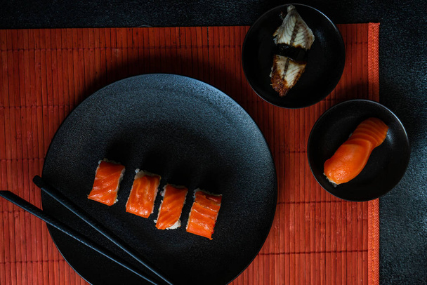 Sushi-Set mit Philadelhia-Rollen serviert auf Steintisch mit Essstäbchen - Foto, Bild