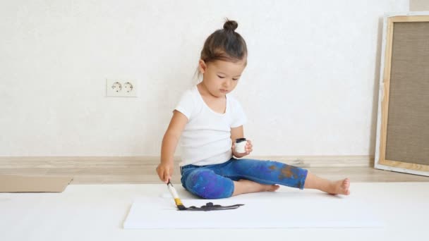 νεαρή κοπέλα αντλεί μαύρη μπογιά από δοχείο σε λευκό χαρτί - Πλάνα, βίντεο