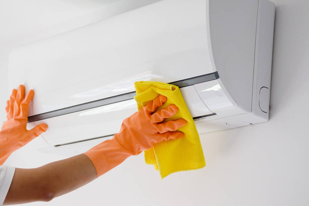 Aziatische man schoonmaken airconditioner met microvezel doek - Foto, afbeelding