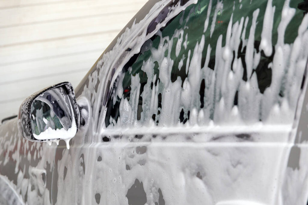Closeup view of motor car window with layer of soap sud during car wash. - Photo, Image