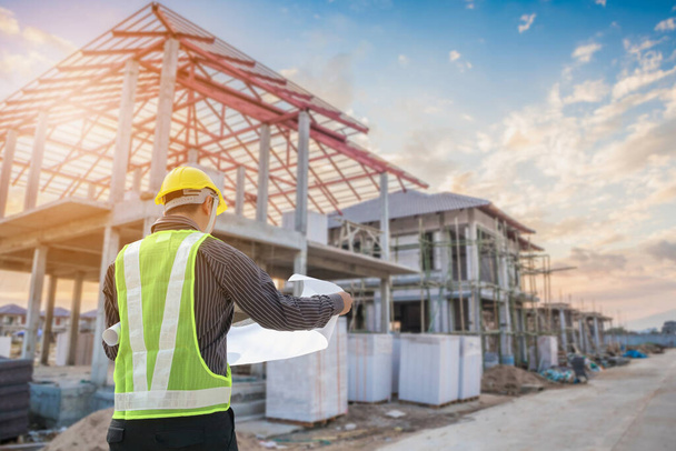 Profesionální inženýr architekt pracovník s ochrannou přilbou a modrotisky papír na staveništi domu stavební zázemí - Fotografie, Obrázek