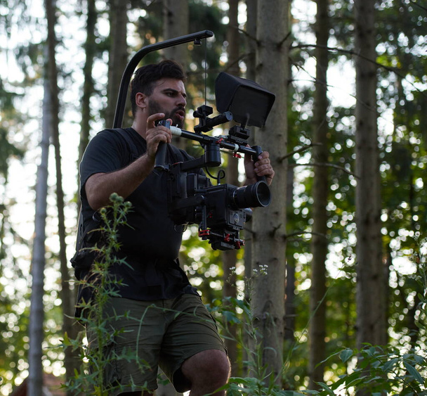 Videographer with Professional Movie Video Camera Gimbal Stabilizing Equipment Taking Action Shoot of Soldiers in Action in Forest - Fotoğraf, Görsel