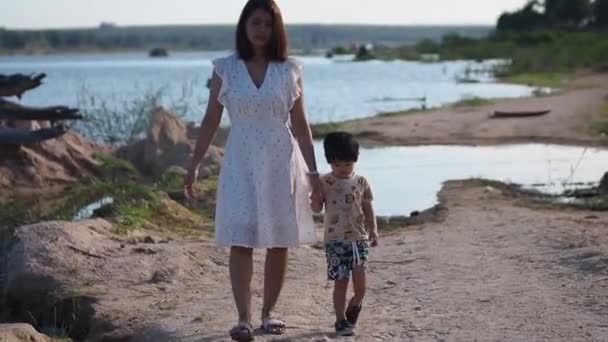 Heureuse mère joyeuse tenant son petit fils marchant en plein air. - Séquence, vidéo