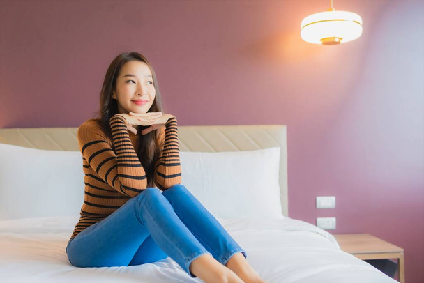 Портрет красива молода азіатка посміхається розслабитися на ліжку в інтер'єрі спальні
 - Фото, зображення