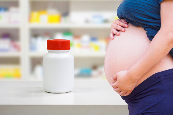 pregnant woman with medicine in the pharmacy store, drug use in pregnancy concept - Foto, Bild