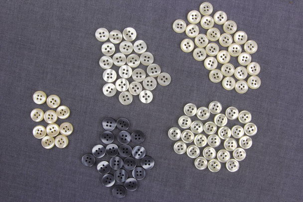 Пластиковые блестящие кнопки для одежды на тканевом фоне. Мода и одежда. Фабричная промышленность - Фото, изображение
