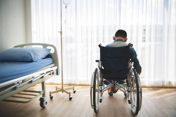 Tekerlekli sandalyeye oturup umutla yan tarafa bakan engelli ayak izi. - Fotoğraf, Görsel