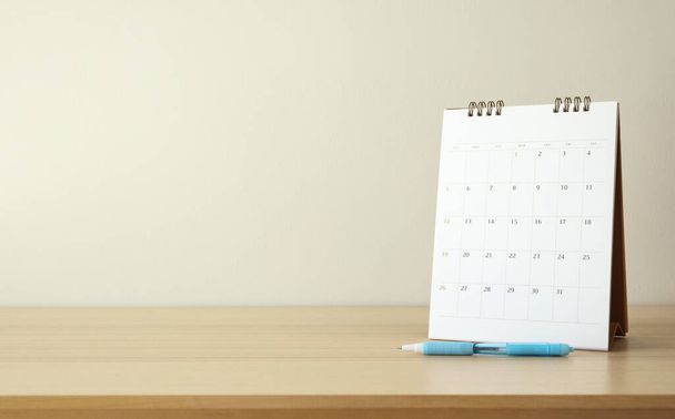 calendario de la página de primer plano en el fondo de la mesa de madera con pluma y cuaderno de planificación de negocios cita concepto de reunión - Foto, Imagen