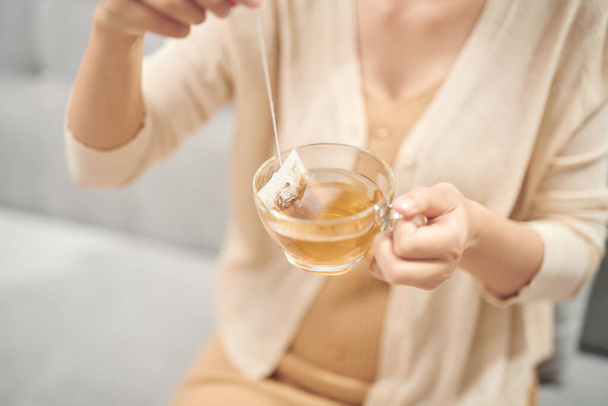 Beltéri felvétel egy mosolygó ázsiai nőről, aki teát iszik.. - Fotó, kép