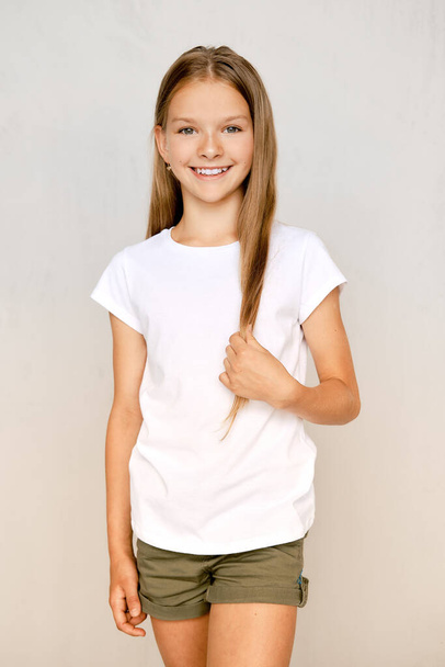 Portrait of positive teenager girl standing with crossed legs and touching hair - Fotoğraf, Görsel