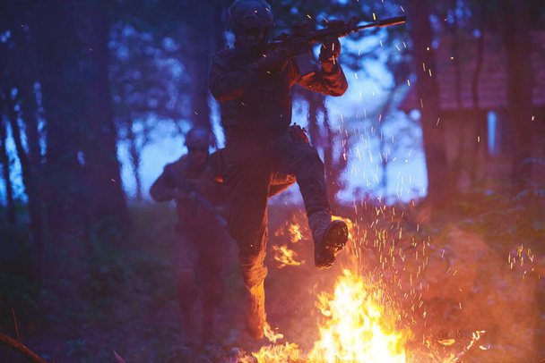 Soldier in Action at Night in the Forest Area. Night Time Military Mission jumping over fire - Photo, image