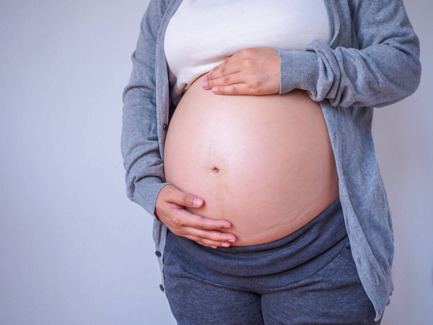вагітна жінка торкається свого живота крупним планом
 - Фото, зображення