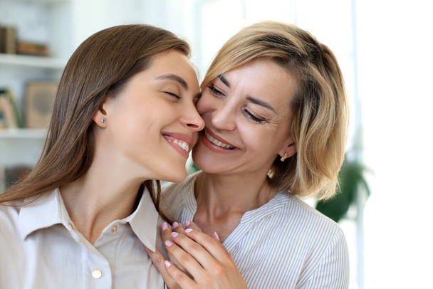 Happy middle aged mother and daughter talking on sofa in living room - Foto, afbeelding