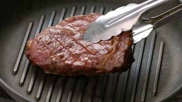 щипці кладуть м'ясо на сковороду шматочок темного м'яса для приготування стейка з риби
 - Кадри, відео