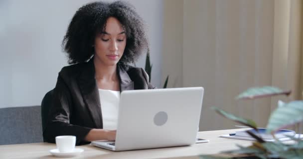 Vooraanzicht van ernstige gerichte vrouwelijke ondernemer of vrij professionele zakenvrouw schrijver zitten aan het bureau, met behulp van laptop voor het typen. e-mail schrijven, studeren en surfen op internet - Video