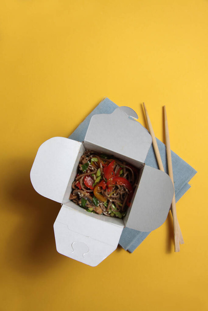 wok box and chopsticks isolated on yellow background flat lay. Image contains copy space - Foto, Bild
