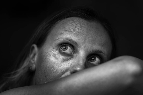 Черно-белый образ женской депрессии или домашнего насилия. Люди, горе и семейное насилие. Крупный план несчастной испуганной плачущей женщины. Остановить насилие! - Фото, изображение