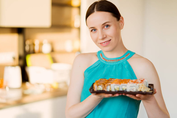 Schöne Frau hält einen Teller mit Sushi-Rollen in ihren Händen - Foto, Bild