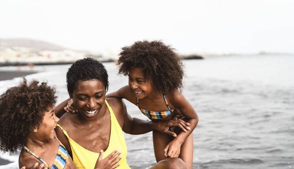 Mutlu Afrikalı aileler yaz tatillerinde plajda oynuyorlar - Afro amerikalılar tatilde eğleniyorlar - ebeveynler yaşam tarzı konseptini seviyorlar - Fotoğraf, Görsel