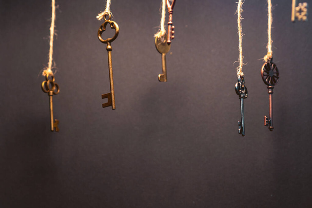 A lot of different old keys from different locks, hanging from the top on strings. - 写真・画像