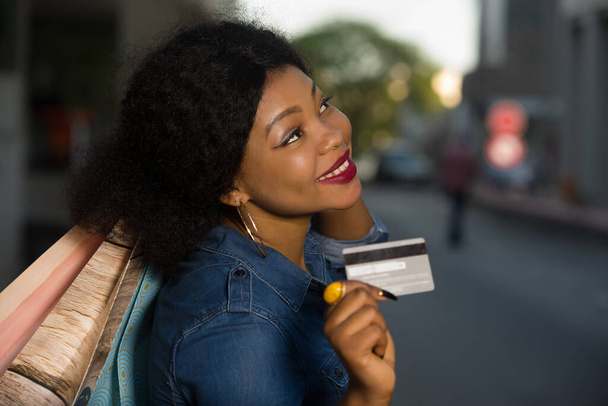 Портрет улыбающейся женщины с кредиткой и сумками в руке в городе - Фото, изображение