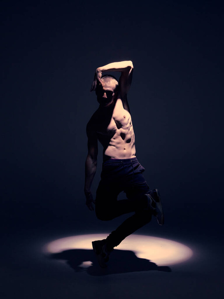 Young man dance without shirt in studio in the spotlight. Dance school poster. Break dance lessons - Photo, Image