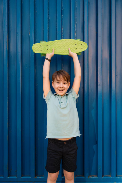 Ένα μικρό αγόρι κρατά μια πράσινη δεκάρα στα χέρια του. - Φωτογραφία, εικόνα
