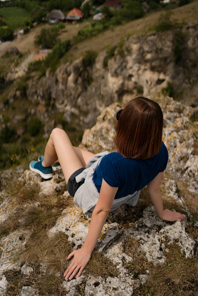 Жінка сидить на скелі насолоджуючись видом
 - Фото, зображення