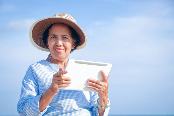 Elderly women hold intelligent tablet communication devices for video chatting, talking with their children. Happy retirement concept - Photo, Image
