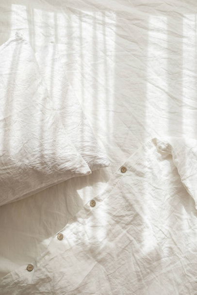 Trendy organic natural linen bedclothes with wooden buttons closeup. Bedding, morning light, bedroom style and design. Rough textile background with wrinkle. - Φωτογραφία, εικόνα