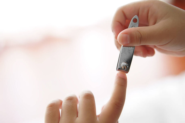 asiatische Kind niedlich oder Kind Mädchen lange Nägel mit schmutzigen und lernen geschnitten Fingernägel durch Hilfe sich selbst und Nagelschneider auf 5 Jahre alt und weißen Ton Hintergrund - Foto, Bild