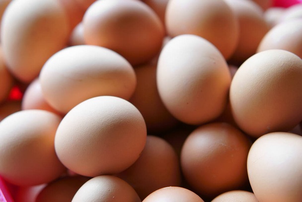 κίτρινη στοίβα ωμών αυγών και νωπά αυγά κότας ή κοτόπουλου και βρασμένα αυγά ή μαλακά βρασμένα σε ροζ καλάθι για διαιτητικά τρόφιμα ή χοληστερόλη σε σούπερ μάρκετ - Φωτογραφία, εικόνα