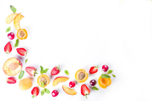 Summer background with fresh fruits and berries on white background. Set of various seasonal fruit and berry  - strawberry, apricots, peach slices, cherry, mint. Flat lay. Summer fruits concept.  - Foto, imagen