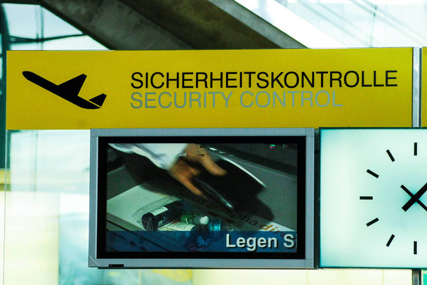 κίτρινο σήμα ελέγχου ασφαλείας στο αεροδρόμιο στα γερμανικά (Sicherheitskontrolle) και αγγλικά (έλεγχος ασφαλείας) - Φωτογραφία, εικόνα