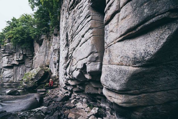 Жінка в червоному пальто стоїть біля кам "яної стіни скелі в каньйоні Буки (Україна). - Фото, зображення